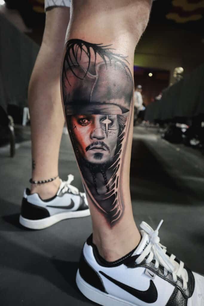 Tatuaje realista en la pierna de un hombre con detalles en negro y gris.